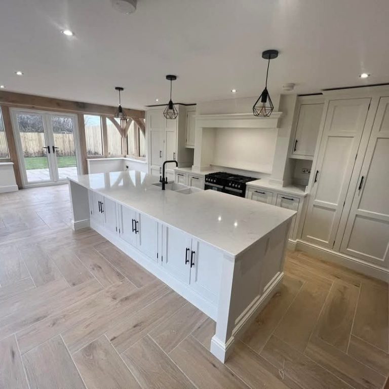 Modern kitchen with a central island, light wood flooring, and large windows.